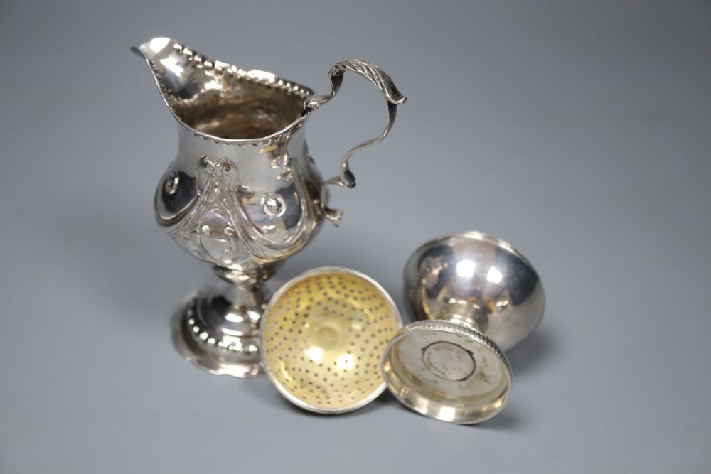 A George III silver inverted pear shaped cream jug, London, 1779 and a George III silver globe shaped pedestal pepperette